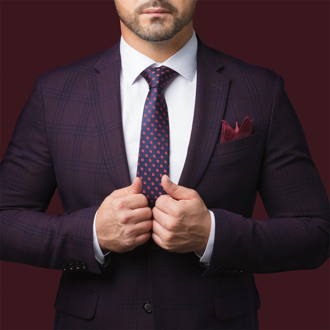 A finished made-to-measure suit in detail, a deep burgundy windowpane check worn with a patterned tie and pocket square